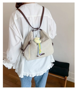 Detail of canvas backpack with leather straps and a cute yellow bird plush charm