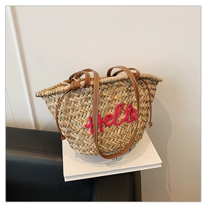 Détail du sac de plage en paille tressée avec broderie Hello rose et cordon de serrage en cuir