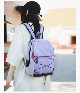 Detail of outdoor lightweight backpack with gray and purple patchwork and elastic cords