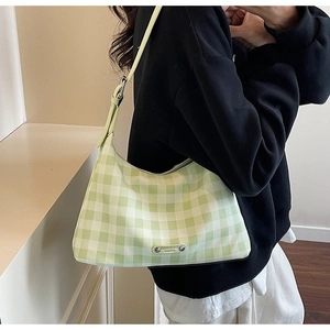 Gros plan du sac porté épaule à damier vert et blanc avec fermeture éclair et logo métal