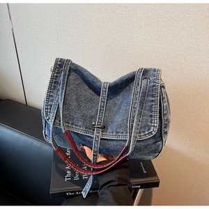 Detailed shot of retro blue denim tote with contrast stitching and woven red handle