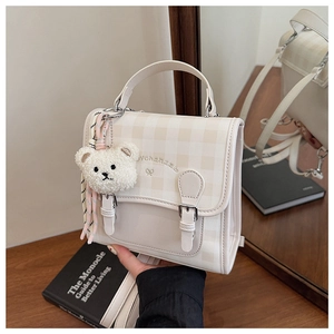 Détail du mini sac à dos à carreaux avec breloque ours en peluche et broderie de marque