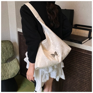 Détail du sac hobo à texture dentelle et boucle papillon argentée sur l'épaule