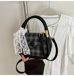 Detail of checkered handbag featuring lace ribbon and polished gold hardware accents
