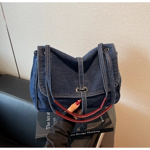 Detail of vintage denim tote bag with brown leather handles and silver metal clasp