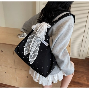 Gros plan sur un sac cabas floral en toile avec un grand nœud en dentelle blanche