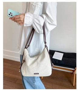 Detail of off-white canvas tote bag featuring brown leather straps and metal side zipper
