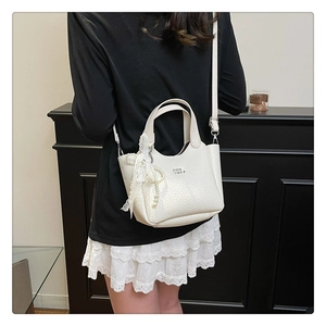 Close-up of white lychee pattern bucket bag featuring lace trim and pearl bead charm