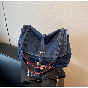 Detailed close-up of retro denim handbag with metal buckle and leather handle