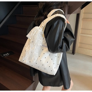 Détail du sac cabas en toile fleurie avec grand nœud en dentelle et étiquette
