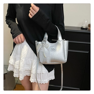 Close-up of silver mini bucket bag with pearl texture and lace bow detail charm