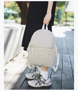 Outdoor shot of a cream-colored lightweight travel backpack with bungee cord details