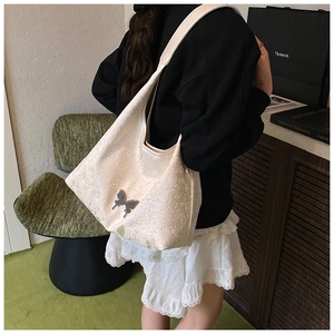 Détail d'un sac hobo blanc en cuir gaufré floral avec pendentif papillon argenté