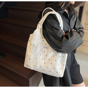 Détail du sac cabas en toile fleurie avec un nœud en dentelle blanche et étiquette