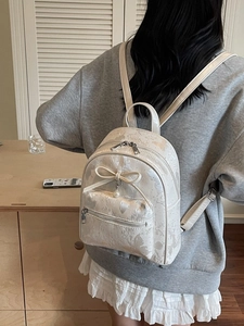 Chic cream bow backpack for women with pearl charm and satin finish on model