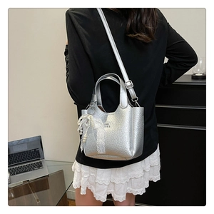 Detail of silver metallic textured crossbody bucket bag with pearl lace charm and strap