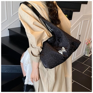 Détail du sac cabas noir avec boucle papillon argentée et texture de points étoilés blancs