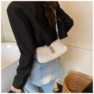 Close-up of a silver glitter shoulder bag with wave texture and metallic lock detail