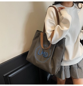 Close-up of thick grey canvas tote bag featuring LMD embroidery and brown straps