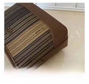 Détail du tissu tissé rayé marron et bord en cuir avec bandoulière chaîne dorée