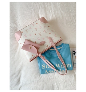 Detail of a large beige tote bag with pink rabbit prints and a matching small pouch