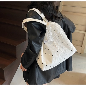 Détail du sac cabas en toile fleurie avec un grand nœud en dentelle et étiquette