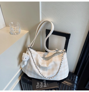 Detail of checkered tote bag with metal chain, bear charm and long shoulder strap