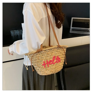 Détail du sac cabas en paille avec broderie Hello rose et bandoulières en cuir marron