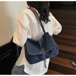 Detail of vintage navy denim flap bag with contrast strap shown on shoulder