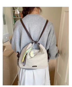 Close-up of minimalist beige canvas hobo bag with brown strap and plush cloud charm