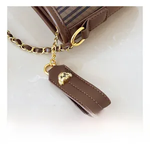 Détail d'un sac cabas en cuir marron avec fermeture éclair chien dorée et bandoulière