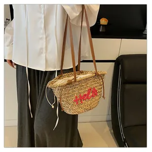 Détail du sac de plage en paille tissée avec broderie Hello rose et anses en cuir