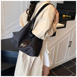 Détail du sac cabas noir à pois avec boucle papillon argentée sur le modèle