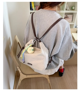 Detail of beige canvas tote with brown leather strap and moon plush charm decoration