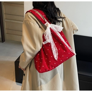 Détail du sac cabas floral rouge en toile avec nœud en dentelle et logo sur la bandoulière