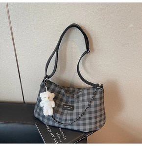 Detail of checkered tote bag with adjustable strap, silver chain, and cute teddy bear charm