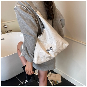 Détail du sac hobo blanc avec motif papillon et accents métalliques argentés chic