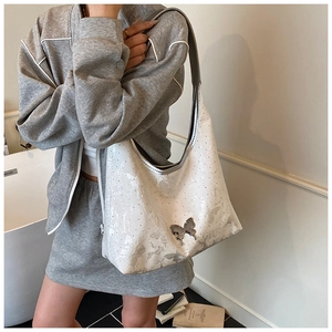 Détail du sac hobo blanc avec boucle papillon argentée et accents en strass brillant