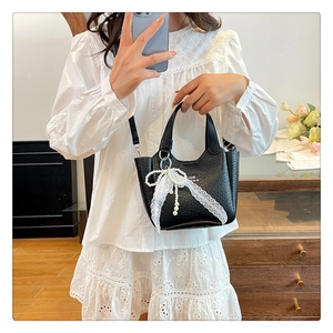Detail of black mini bucket bag with lace bow and pearl charm shown in a mirror selfie