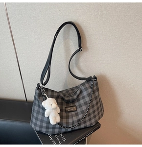 Detailed close-up of grey plaid crossbody bag with metal chain and plush bear charm