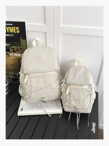 Detail of beige nylon backpack set with crinkled texture and front drawstring design