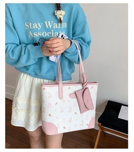 Detail of printed large tote bag with cute cartoon rabbit pattern and small coin purse charm