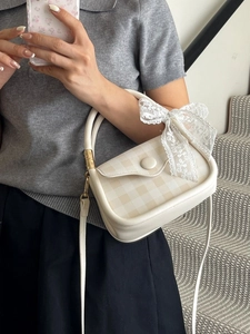 Chic beige plaid square handbag with lace bow detail held by model on stairs