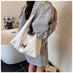Détail du sac cabas blanc avec boucle papillon argentée et bandoulières métalliques
