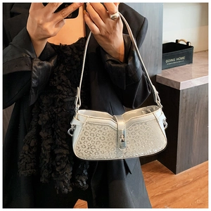 Detail view of silver baguette bag with embossed leopard texture and metal lock