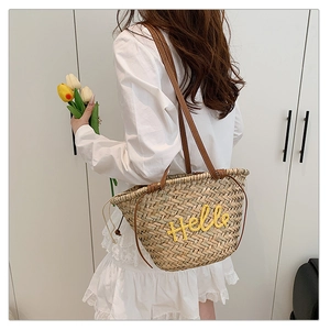 Détail d'un sac de plage tressé avec broderie Hello jaune et bandoulière en cuir marron