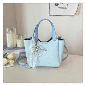 Close-up of light blue litchi pattern bucket bag with pearl lace bow charm detail