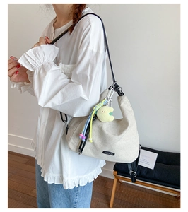 Detail of beige canvas hobo bag with black strap and star charm accessory