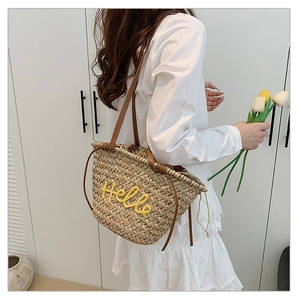Détail du sac cabas en paille tissée avec broderie Hello jaune et anses en cuir brun