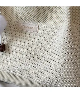 Détail du sac en tricot blanc cassé avec maille évidée et étiquette en cuir chic